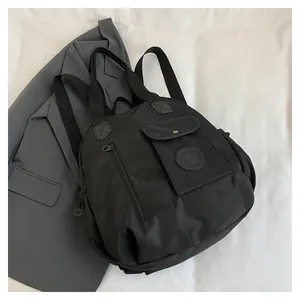 Close-up of black nylon travel bag with buckle pocket and circular brand logo detail