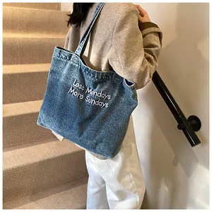 Blue washed denim tote bag with 'Less Mondays More Sundays' embroidery on shoulder strap