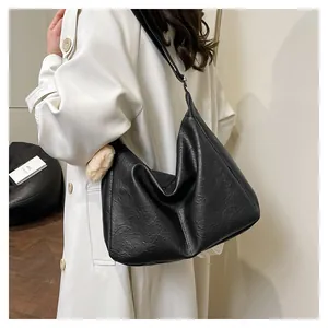 Detail of black faux leather hobo bag with pleated texture and plush pompom charm