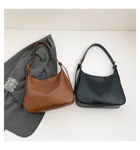 Detail view of large tote bags in brown and black faux leather with adjustable strap