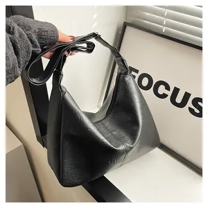Detail of a black hobo bag showing pleated leather texture and a silver metal buckle