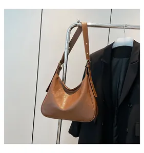 Detail of vintage brown textured leather hobo bag with adjustable strap on a hanger