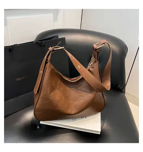 Detail of caramel pleated leather texture and golden metal hardware on shoulder bag