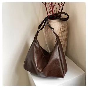 Macro shot of dark brown pebbled faux leather texture and silver buckle on hobo bag