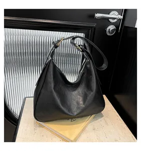 Close-up of black Hobo bag with natural wrinkled leather texture and wide strap