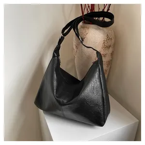 Detailed view of black tote bag with lychee texture and adjustable wide shoulder strap