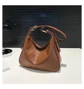 Detail of caramel leather tote bag with adjustable strap and shiny gold hardware