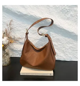 Detail view of brown pleated faux leather hobo bag with gold hardware and adjustable strap