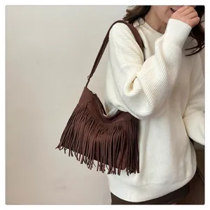 Dettaglio di una borsa marrone con frange in morbida pelle scamosciata e stile boho