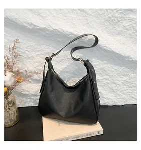 Detail of minimalist black hobo bag showing wrinkled faux leather texture and gold buckle