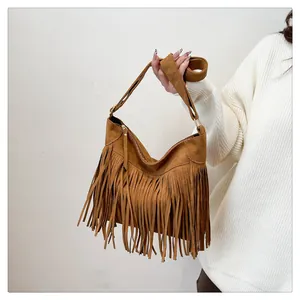 Dettaglio della borsa tote in pelle scamosciata marrone scuro con nappe e fibbia dorata