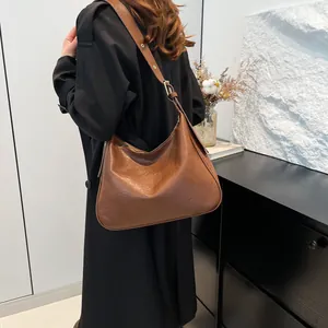 Caramel brown vintage textured leather tote bag worn by model in minimalist studio setting