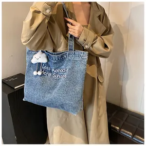 Detail of blue denim tote bag with Less Mondays More Sundays print and cloud charm