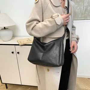 Classic black faux leather tote bag worn by a model in a minimalist home setting