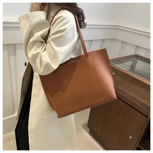 Détail du grand sac cabas en cuir marron avec barre métallique argentée et poche frontale