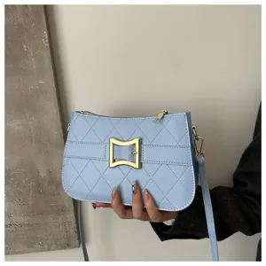 Détail d'un sac à main matelassé bleu clair avec grande boucle en métal doré et zip