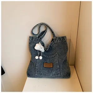 Close-up of vintage denim tote bag with brown leather patch and white plush cloud charm