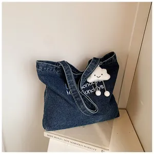 Detail of dark blue denim tote bag texture with white lettering and cloud charm