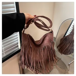 Dettaglio della borsa tote in pelle scamosciata marrone con frange e fibbie dorate