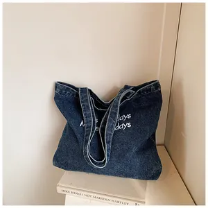 Detail of dark blue denim tote bag with white Holidays embroidery on vintage fabric