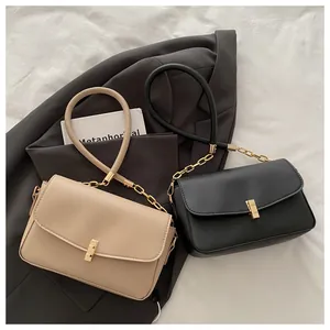 Details eleganter Handtaschen mit Goldkette und Metallschnalle auf grauem Blazer