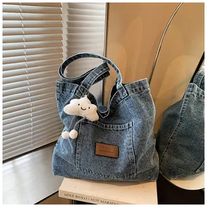 Close-up of vintage denim tote bag showing leather logo patch and plush cloud keychain