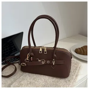 Detailopname van chocoladebruine Boston tas met gouden rits en leren handvat op bureau