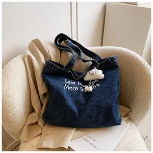 Detail of dark blue denim tote bag featuring white embroidery and fluffy cloud charm