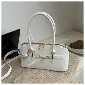 Detailopname van witte lederen schelptas met gouden ritsen en metalen riemhaken