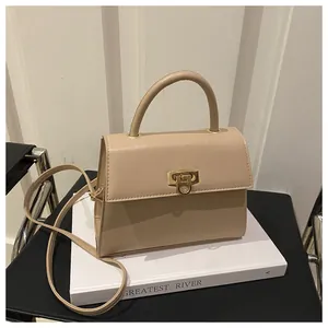 Detail der beigen Ledertasche mit goldenem Drehverschluss und rundem Tragegriff