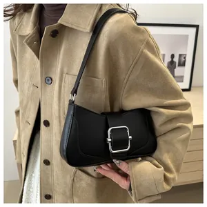 Detail of black matte shoulder bag with a bold silver square buckle on smooth leather
