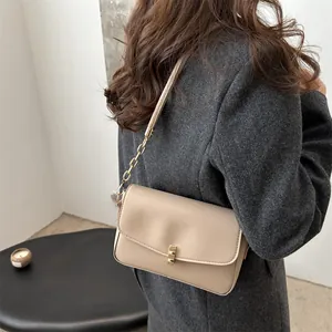 Beigefarbene rechteckige Umhängetasche mit goldener Kette am Model für einen eleganten Look