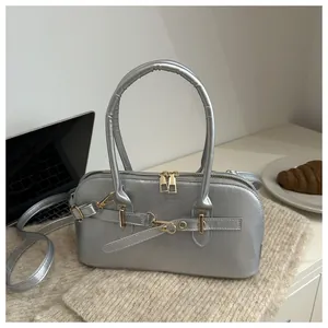 Zilveren PU-handtas in schelpvorm met goudkleurige hardware in een lifestyle-setting
