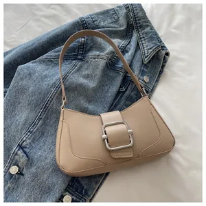 Macro shot of stylish beige faux leather handbag with a large silver metal buckle detail