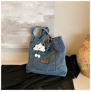 Detailed close-up of blue denim tote bag with leather label and white cloud plush charm