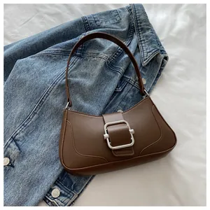 Detailed view of brown leather bag with silver buckle on blue denim jacket background