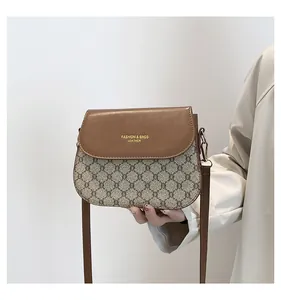 Detail of a brown leather flap shoulder bag with beige monogram pattern and gold lettering