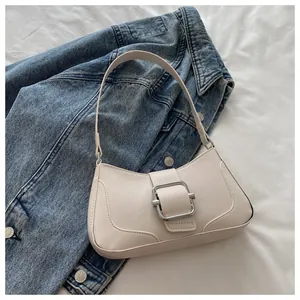 Detail of a chic cream shoulder bag with a large silver buckle on denim background