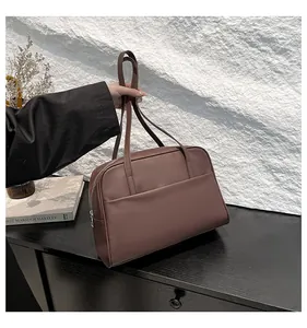 Détail d'un sac cabas en cuir marron montrant la texture lisse et la poche extérieure