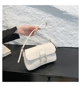 Close-up of cream white handbag featuring a luxury gold horseshoe buckle and matte texture