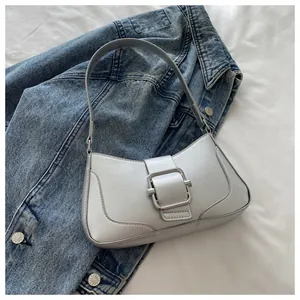 Detail of silver metallic baguette bag with oversized buckle on denim jacket background