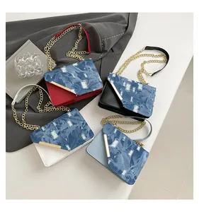 Flat lay of square chain bags with distressed denim flaps in red black white and blue