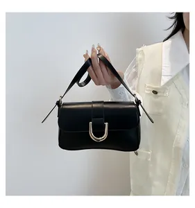 Close-up of minimalist black leather handbag featuring a signature golden U-shaped clasp