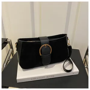 Détail du sac d'épaule en cuir noir avec boucle dorée et finitions mates texturées