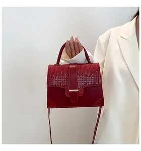 Detail of red leather handbag showing crocodile pattern texture and gold metal buckle