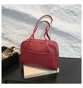 Vue détaillée du sac cabas rouge foncé en cuir avec fermeture éclair sur fond roche