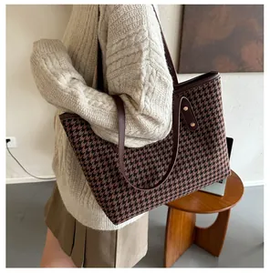 Détail du sac cabas en laine à carreaux avec anses en cuir marron et rivets