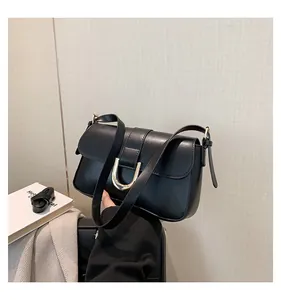 Close-up of a black leather handbag featuring a stylish gold horseshoe metal buckle clasp