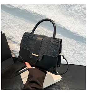 Detail of black crocodile texture leather bag with elegant golden metal bar clasp