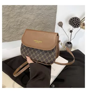 Close-up of vintage brown leather crossbody bag with retro floral pattern and magnetic flap